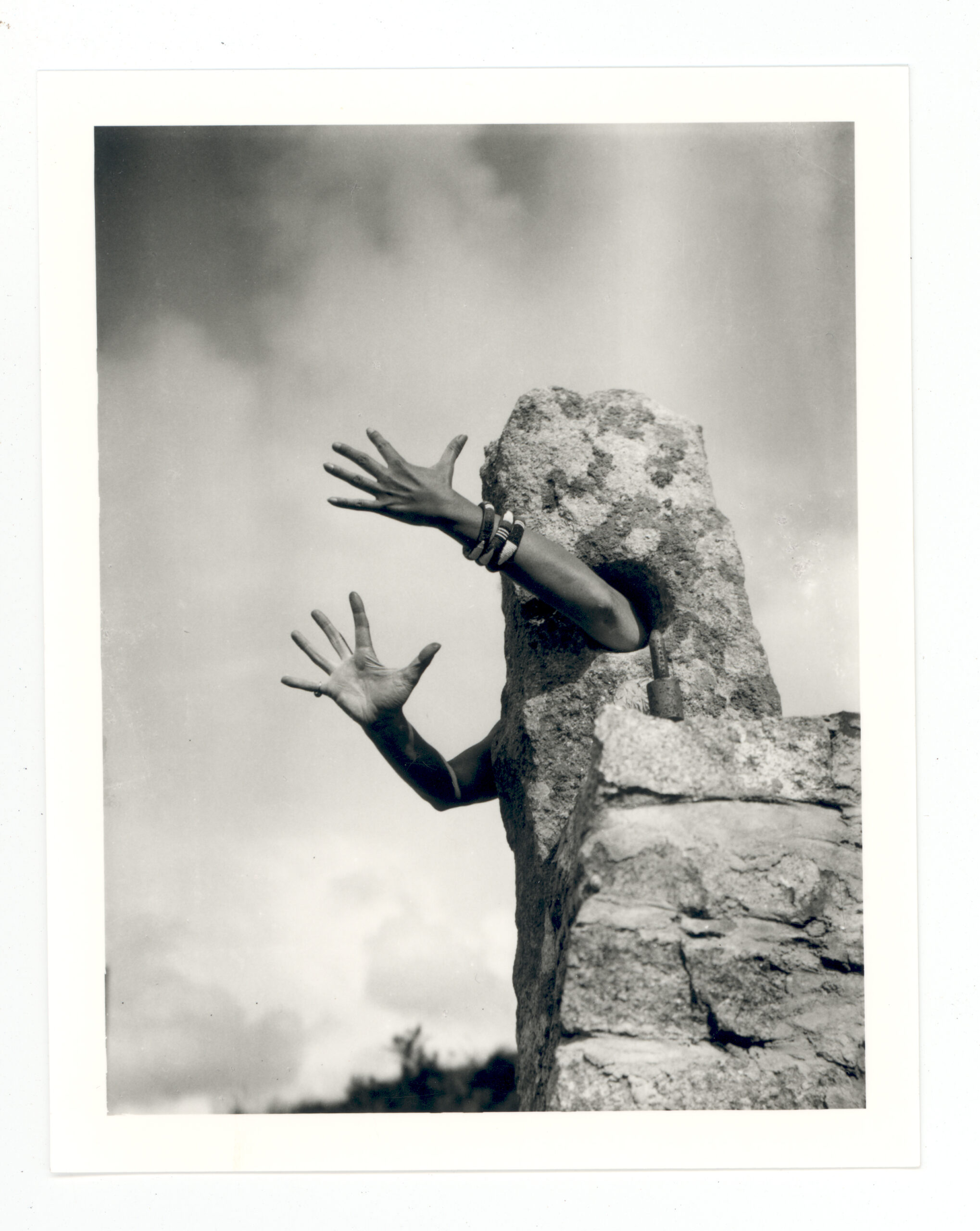 A photo of Claude Cahun's arms stretching out of rock. The fingers appear webbed, with tendons straining against the skin so that the human feature appears as inhuman as possible.This picture is presented as part of the exhibition Claude Cahun: Beneath This Mask