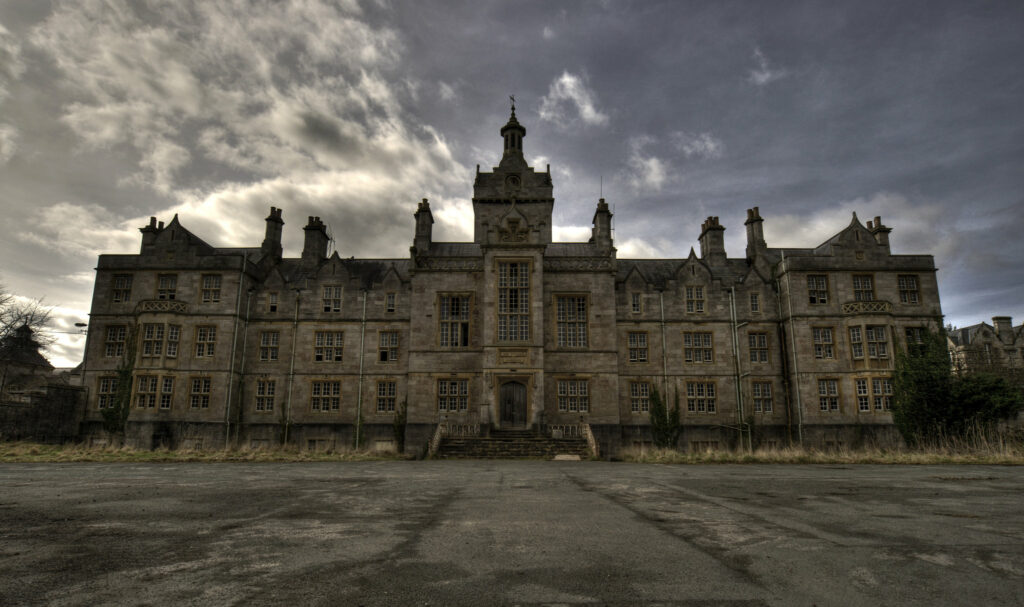 Beth McAulay explores the contemporary significance of the North Wales Hospital, or Denbigh Asylum. The picture shows the hospital against a dusky sky.