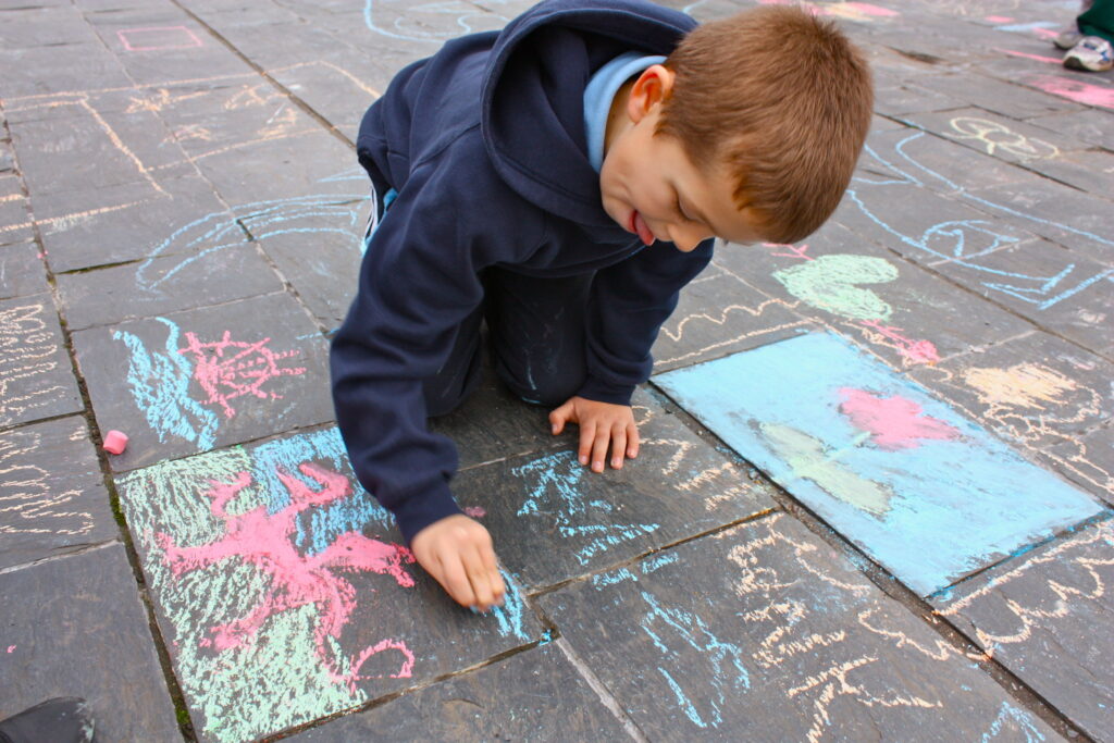A child playing with chalk outside the Senedd