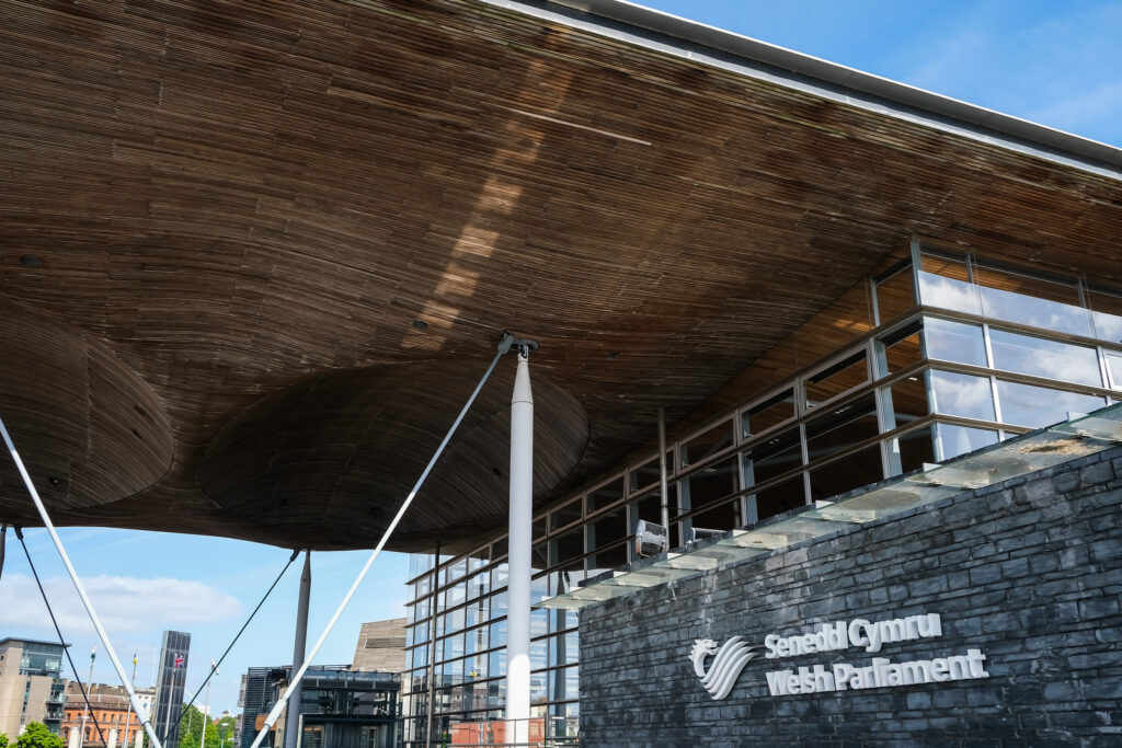 A picture of the Senedd seen from the outside, against a blue sky. In the week the Senedd turned 25, substantial reforms to the way the parliament works were passed, marking the next chapter in the ever-evolving story of devolution.