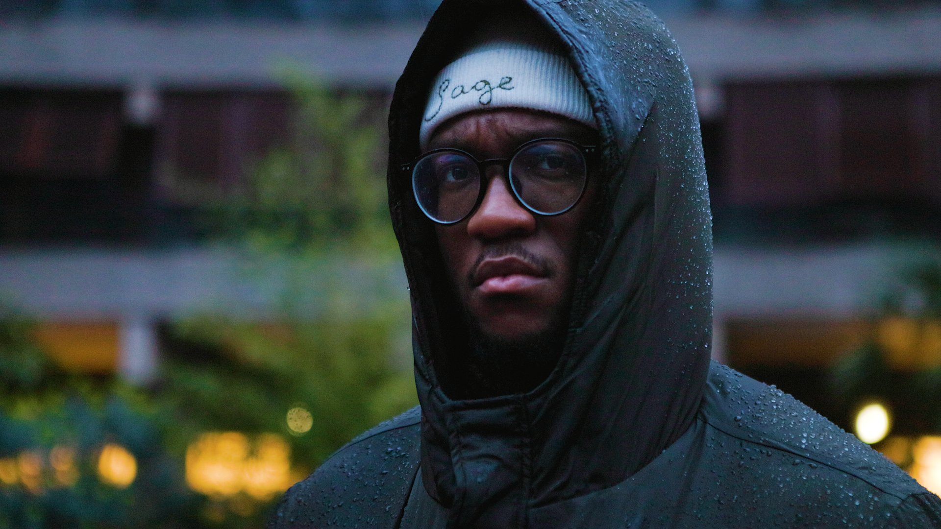 A picture of Welsh and English language rapper Sage Todz facing the camera against a rainy background.