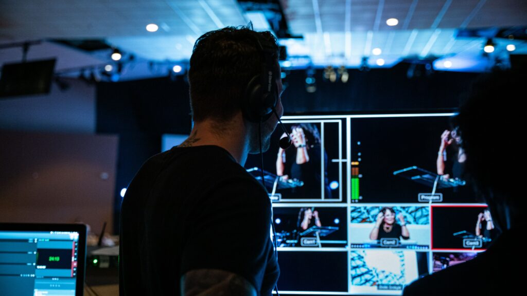 Photo by Carlynn Alarid on Unsplash A man looking at a series of screens showing television shows being recorded. The article it relates to is about the role of public interest journalism in Wales.