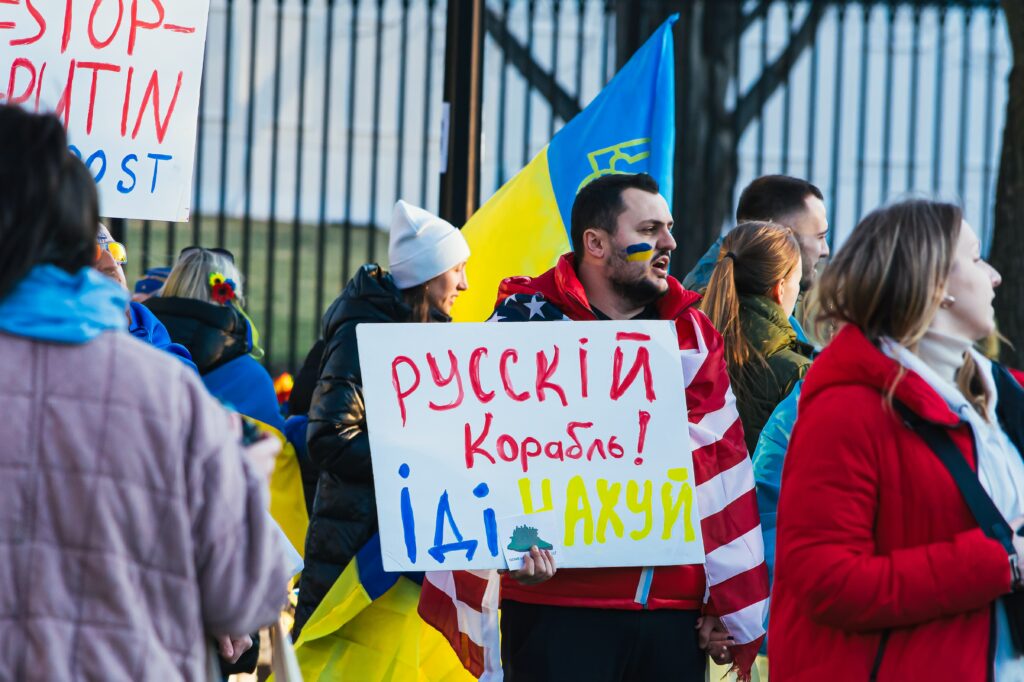 A picture of a protest against the war in Ukraine, showing men and women with flags.