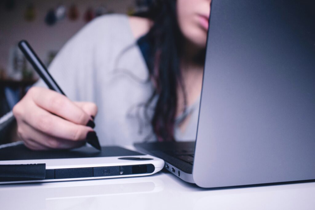 A woman studying on a computer. Only part of her face is visible. The article discusses the uncertain future of the UK Shared Prosperity Fund and its likely impact in Wales