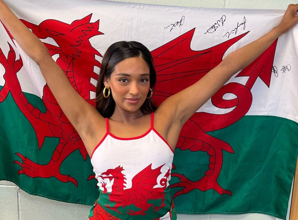 Woman standing in front of a Welsh flag.