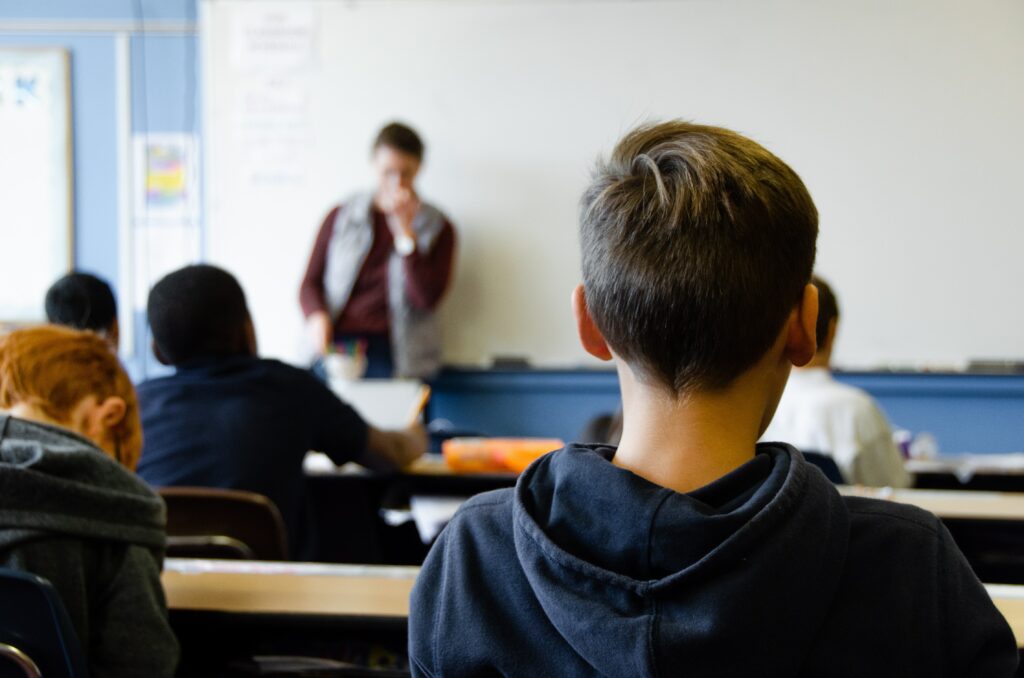 The picture shows children looking towards a whiteboard in a classroom. They seem to be listening intently. The picture serves to illustrate an article about global citizenship.