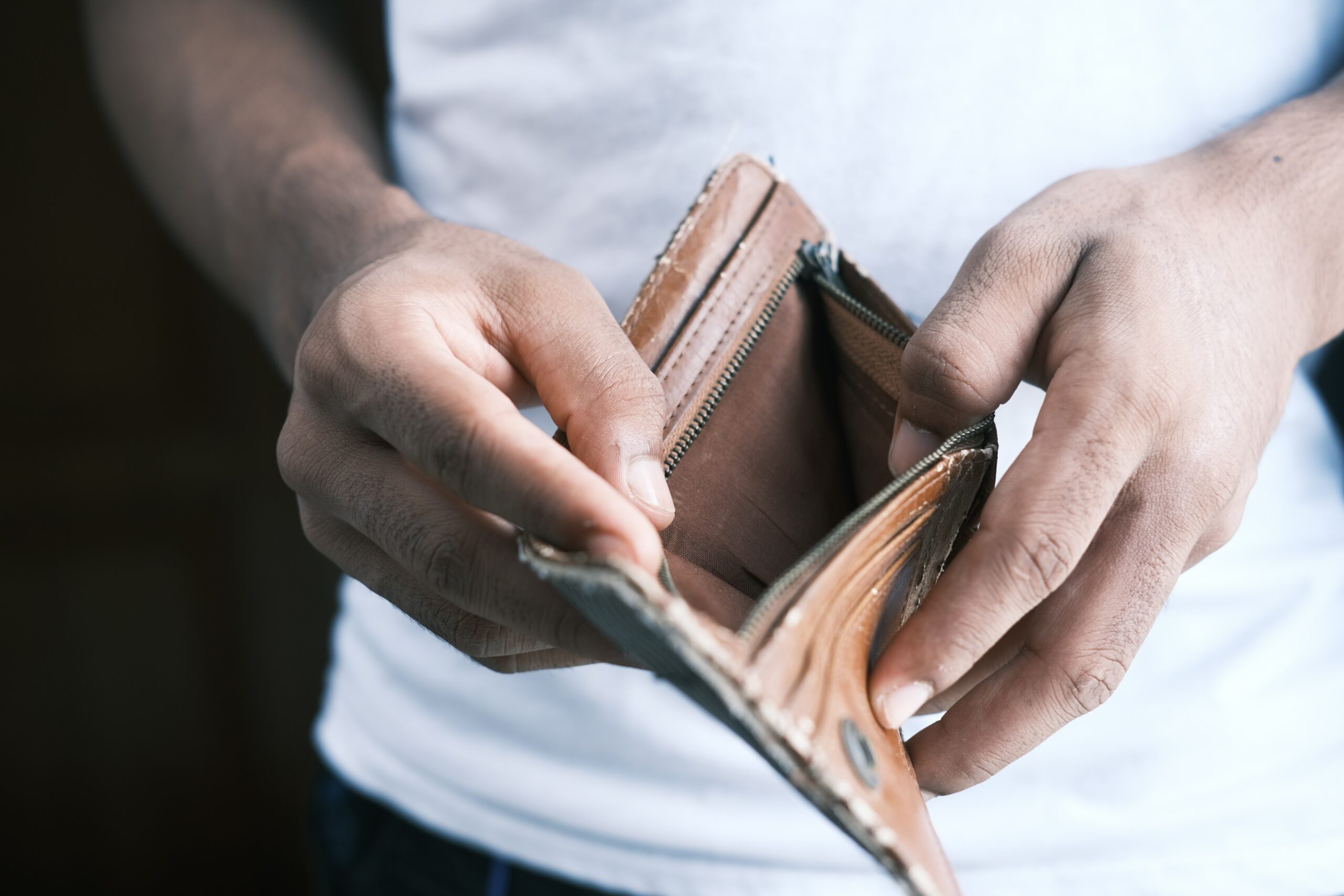 A man looking inside his wallet and finding it empty