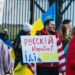 A picture of a protest against the war in Ukraine, showing men and women with flags.